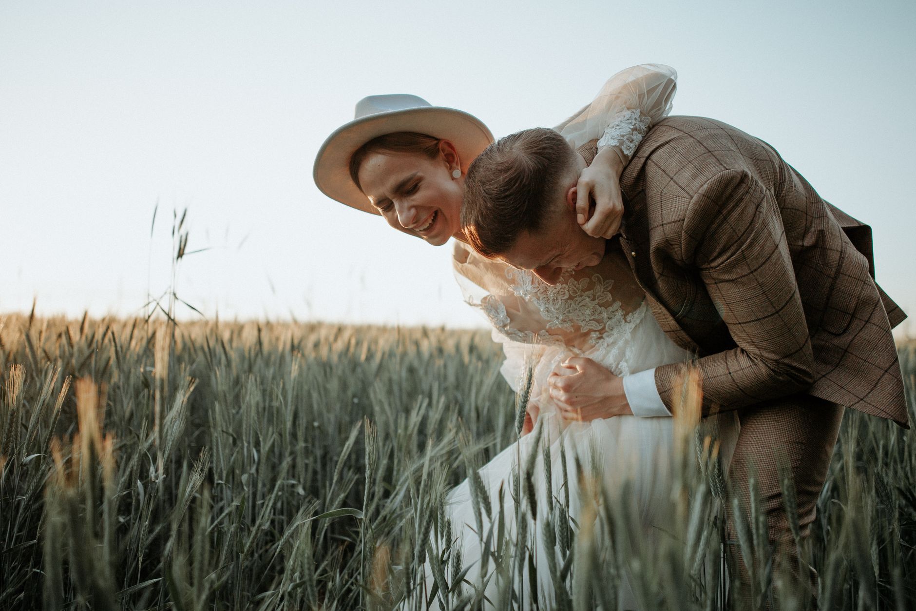 A couple laughing in a sunlit Kansas wheat field